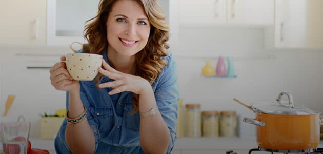 Woman standing at kitchen counter with a coffee cup
