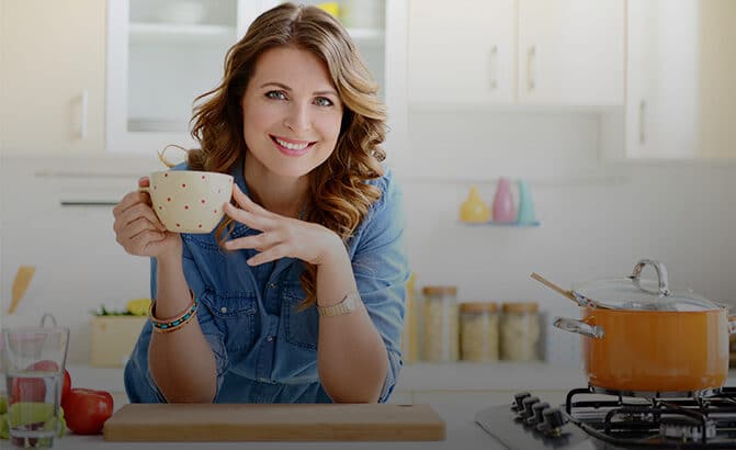 Woman standing at kitchen counter with a coffee cup