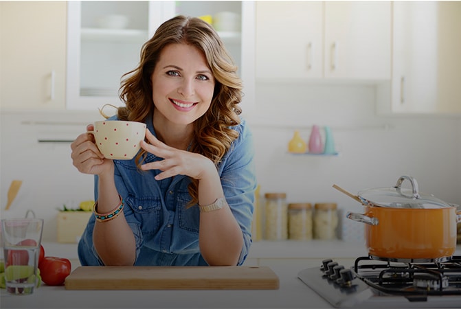 Woman standing at kitchen counter with a coffee cup