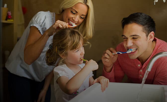 Family of three brushing their teeth