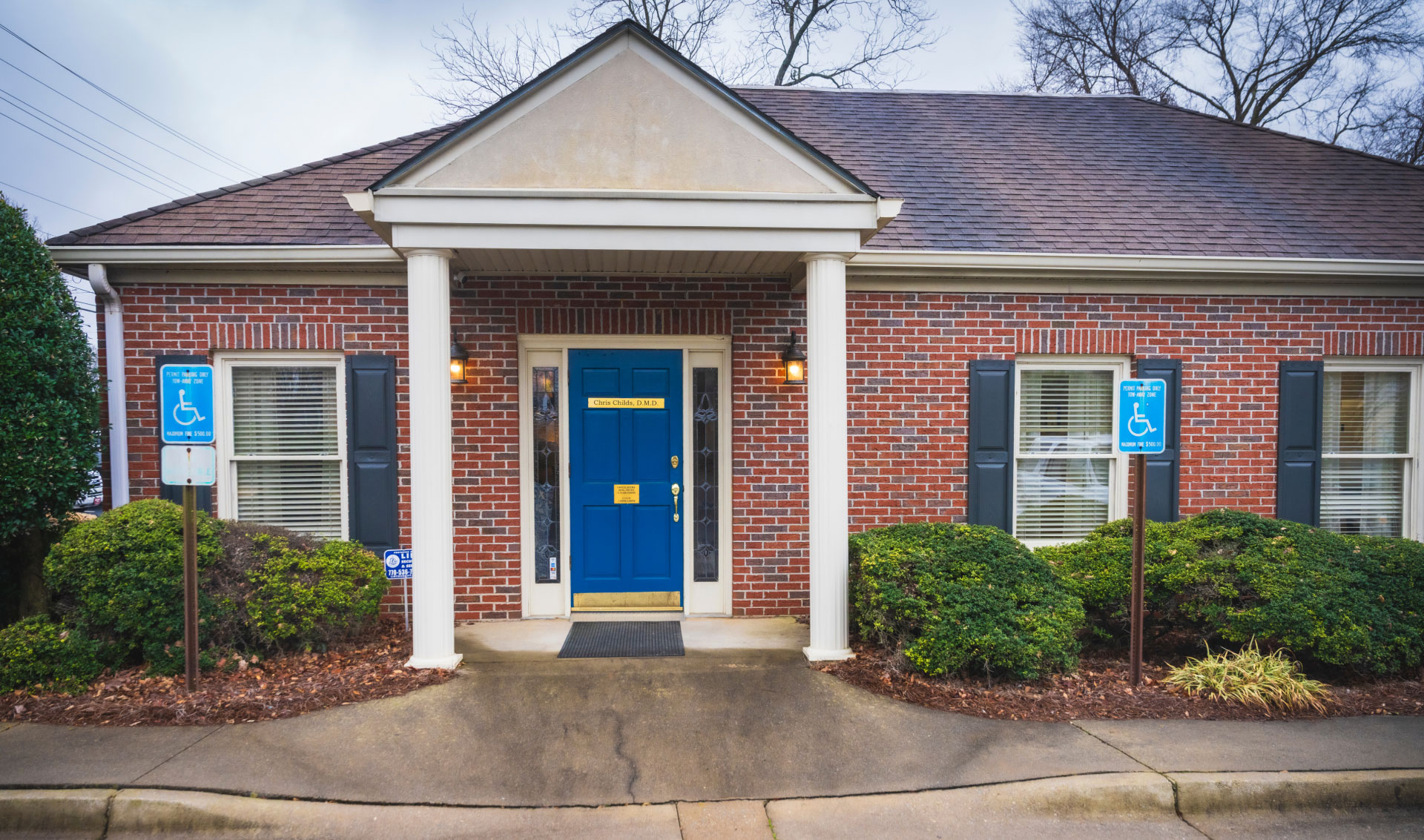 Chris Childs DMD building exterior with red brick and a blue front door