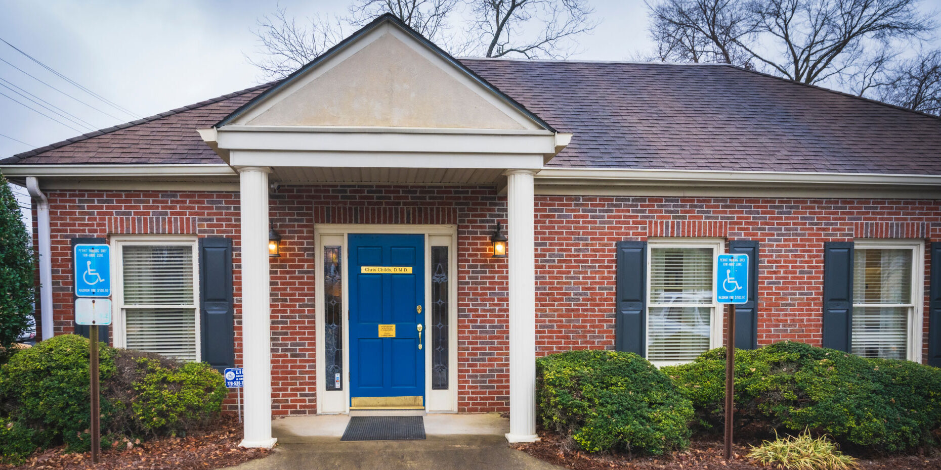 Chris Childs DMD building exterior with red brick and a blue front door